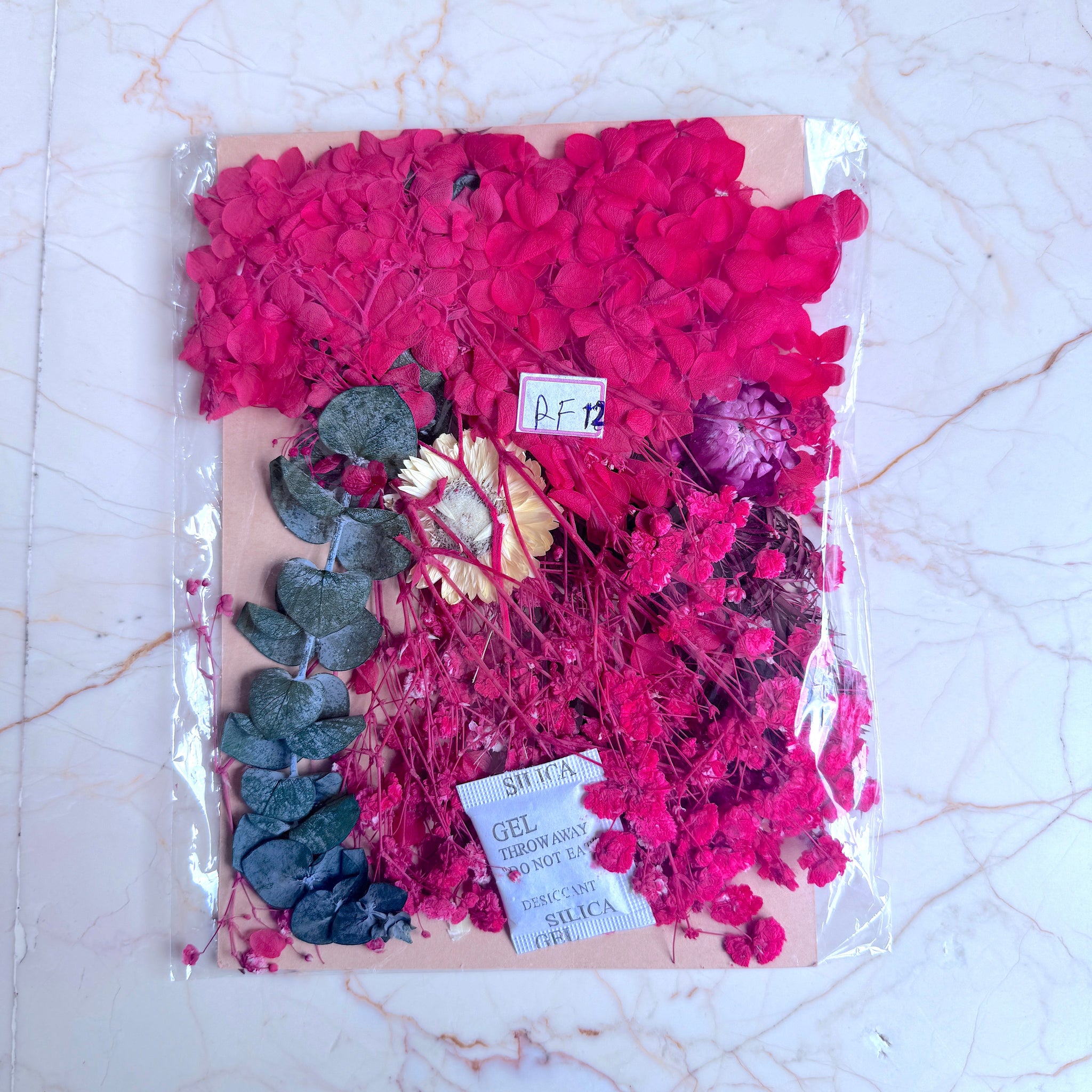 Packaged pink flowers with green leaves on a marble surface Dry Flower Packet