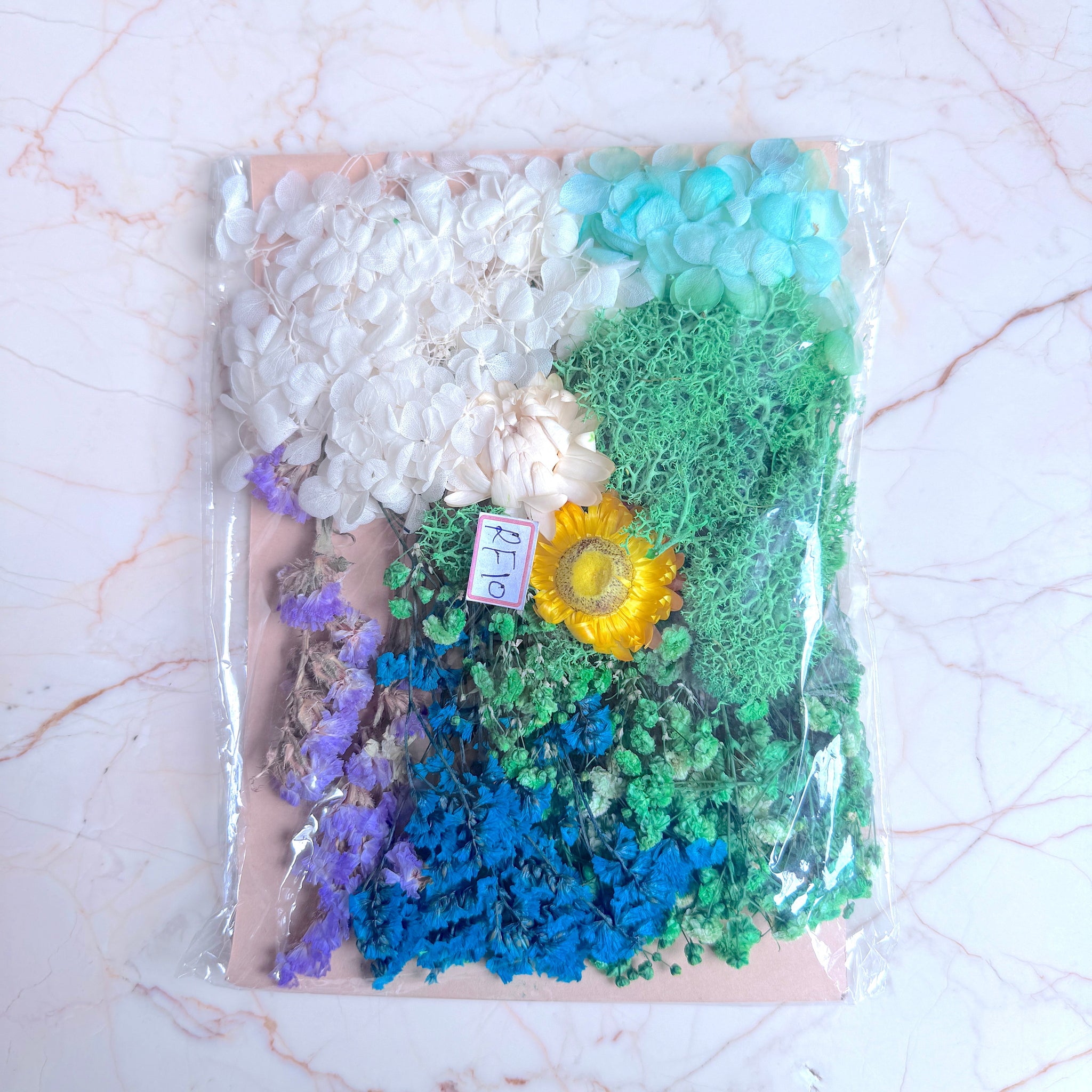 Packaged craft materials including flowers, and a sunflower on a marble surface.