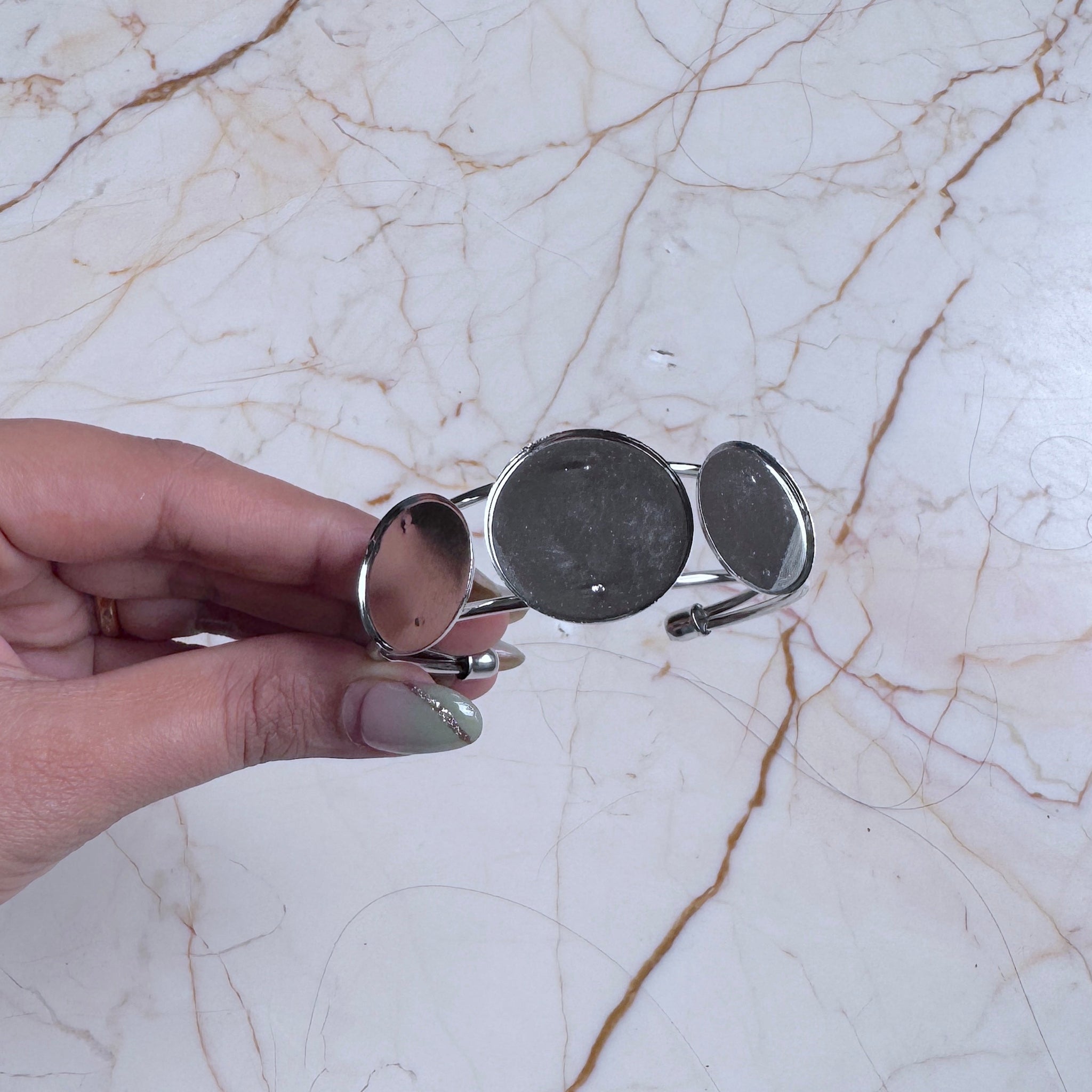 Hand holding a bracelet on a marble surface