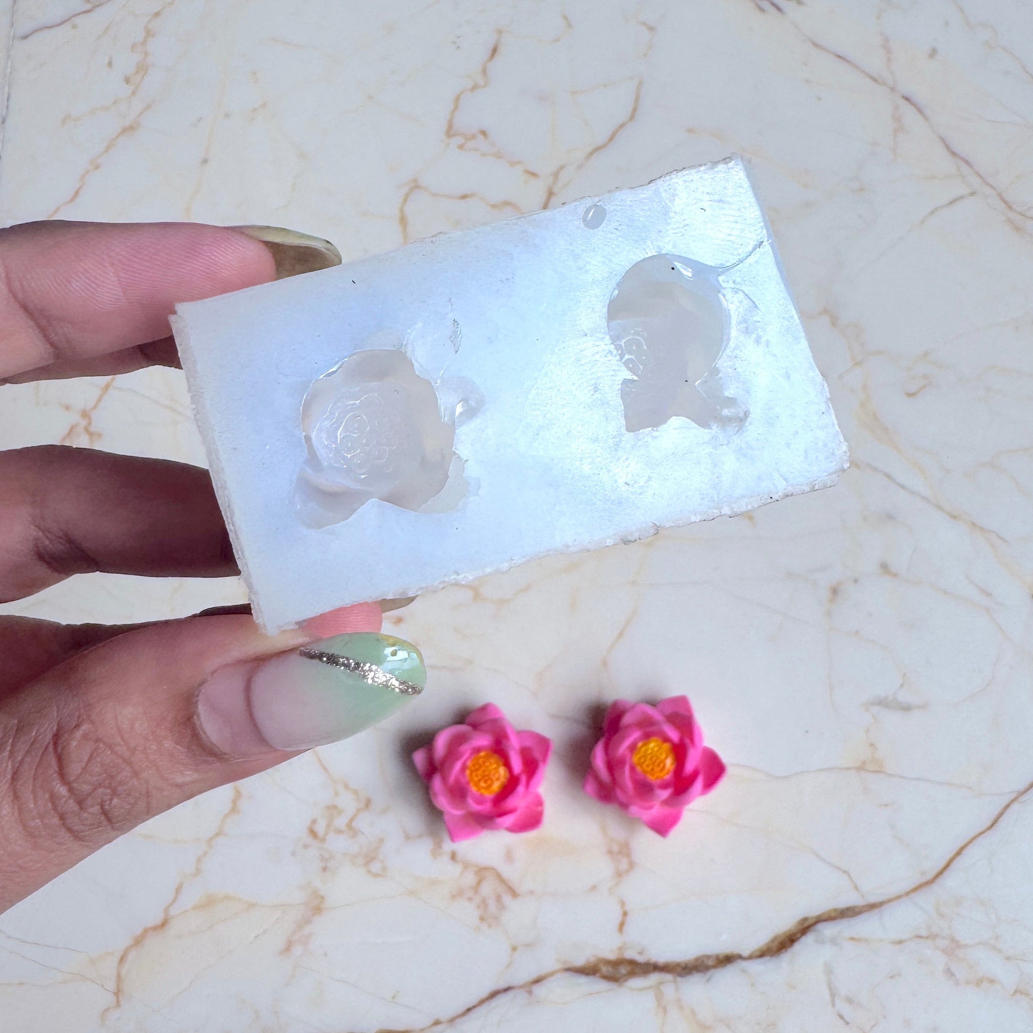 Hand holding a silicone mold with floral designs on a marble surface
