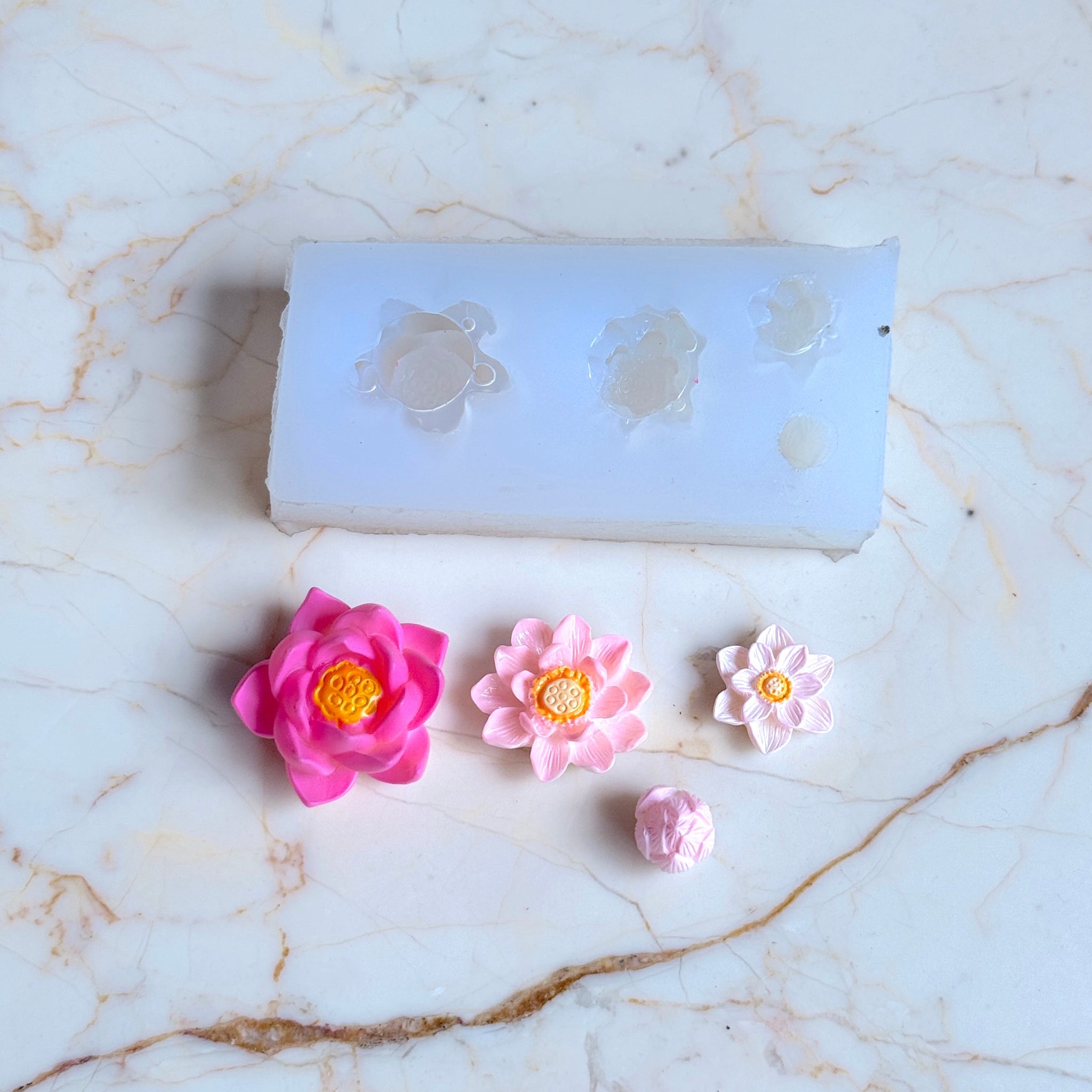 Set of flower-shaped earrings on a marble surface with a silicone mold.