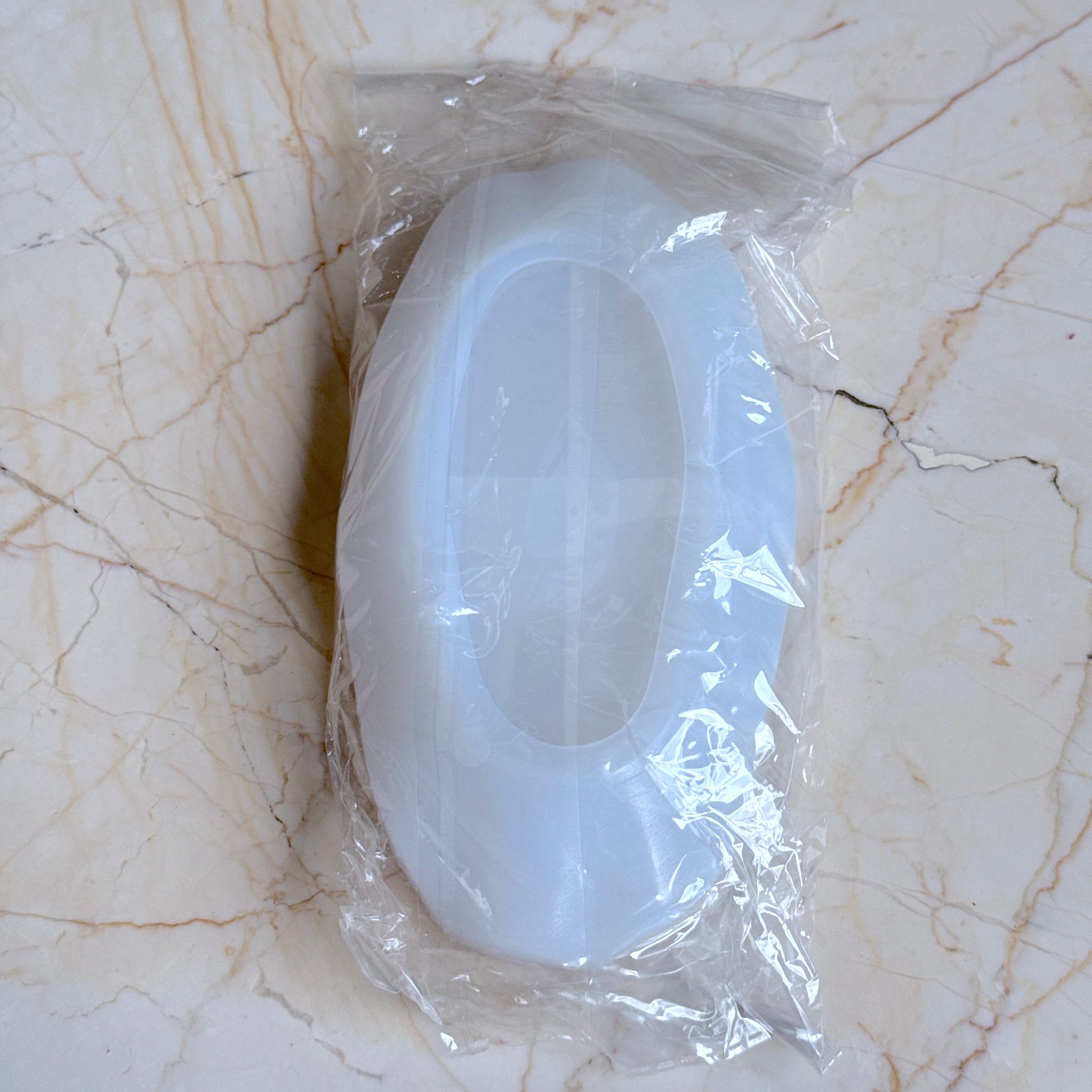 White plastic component in clear plastic wrap on a marble surface