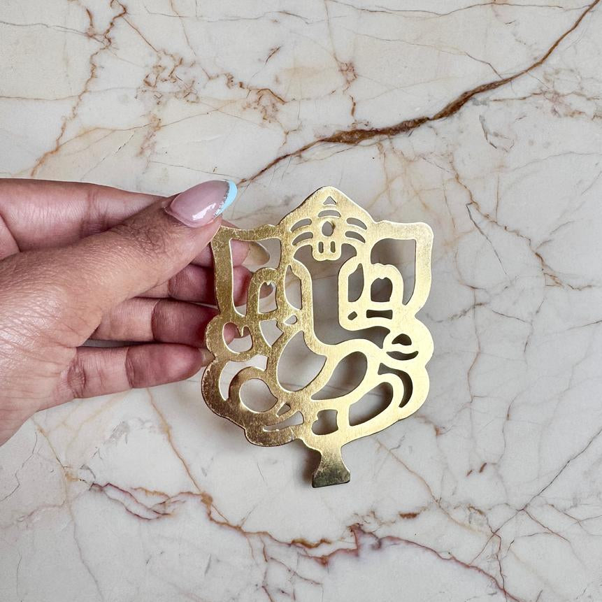 Gold decorative item held by a hand on a marble surface