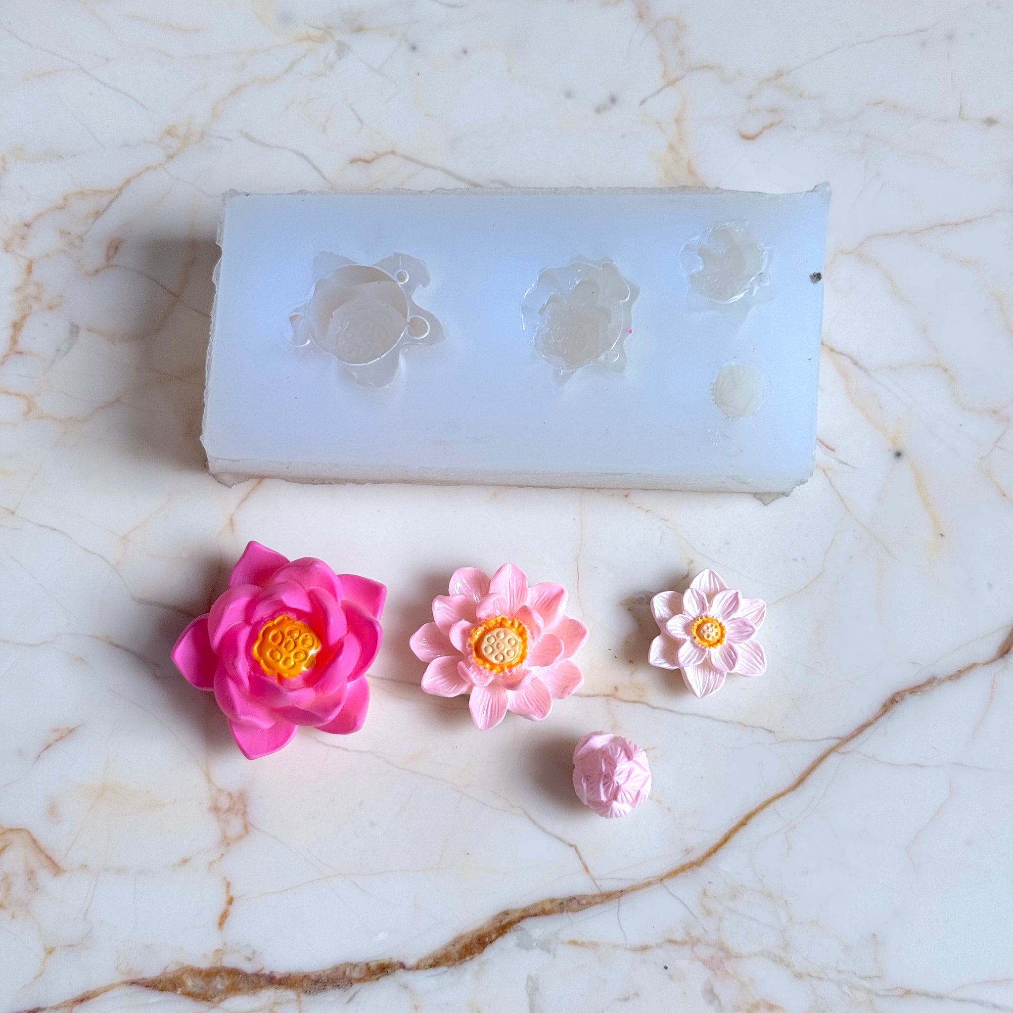 Pink flower-shaped candies with a mold on a marble surface