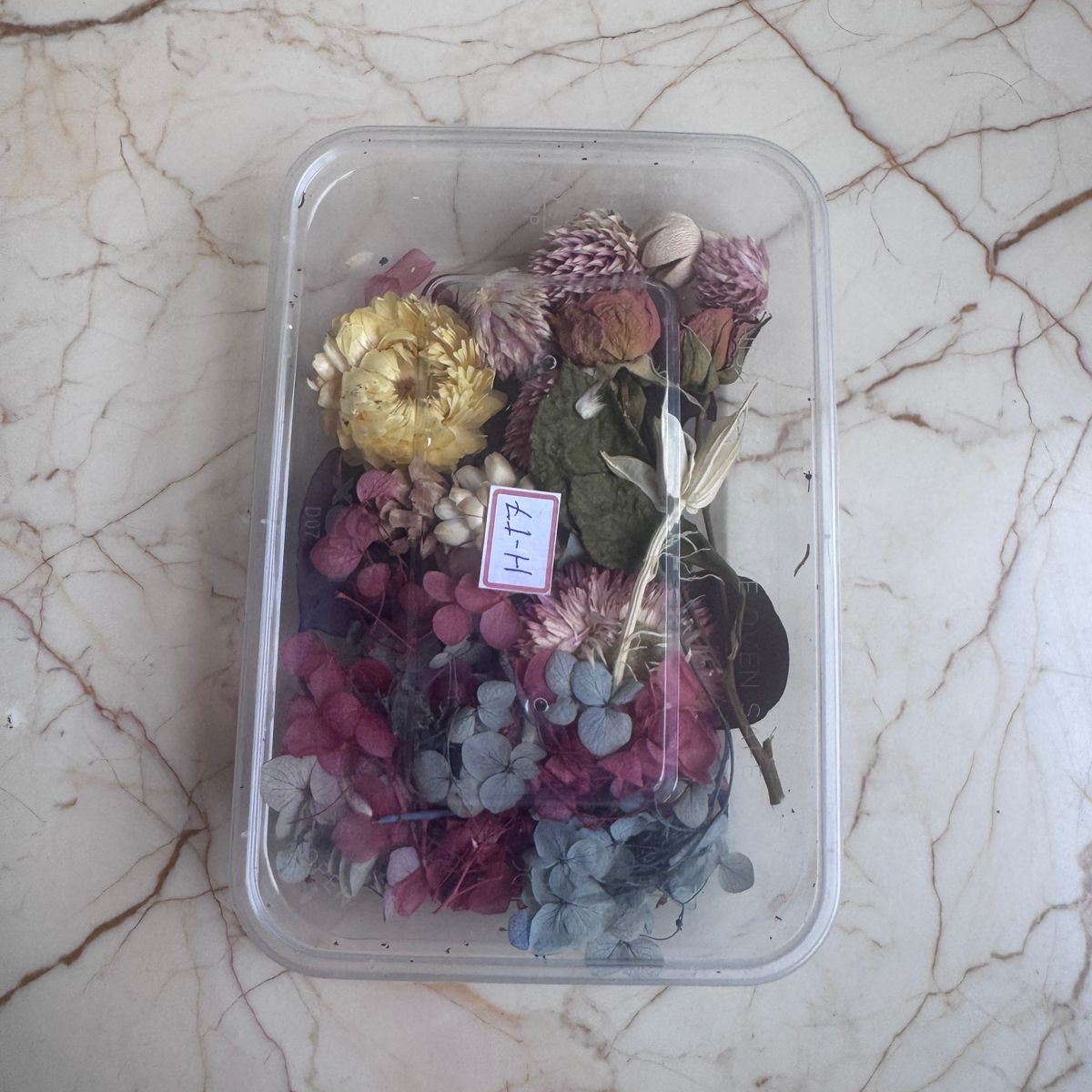 Container of dried flowers with a price tag on a marble surface