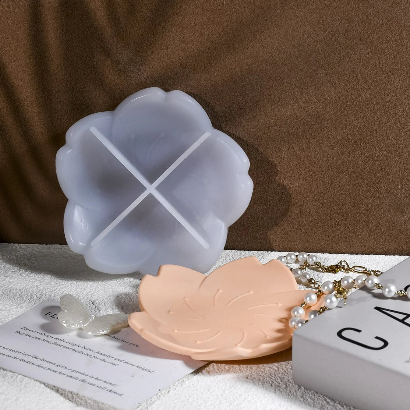 Two silicone leaf-shaped molds on a textured surface with a brown background