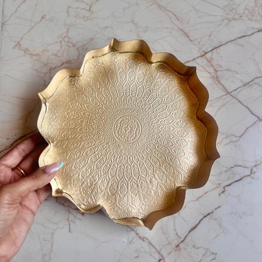 Gold decorative plate held by a hand on a marble surface