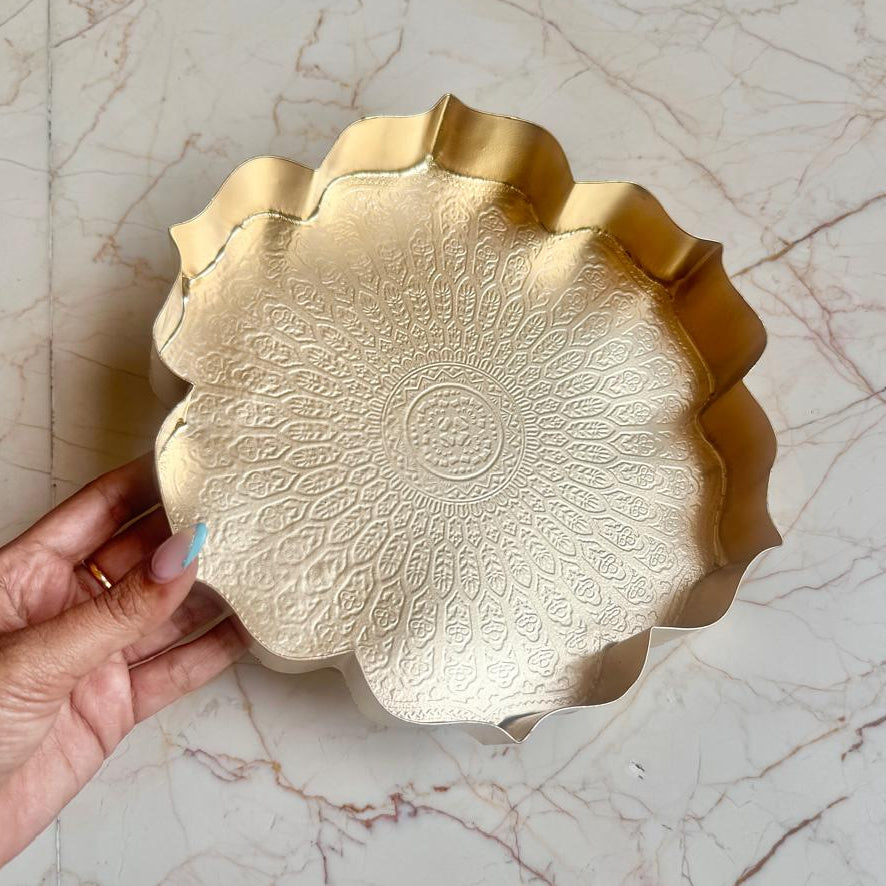 Gold decorative plate held by a hand on a marble surface