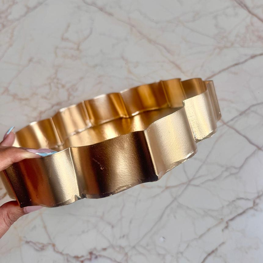 Gold bracelet held by a hand on a marble surface