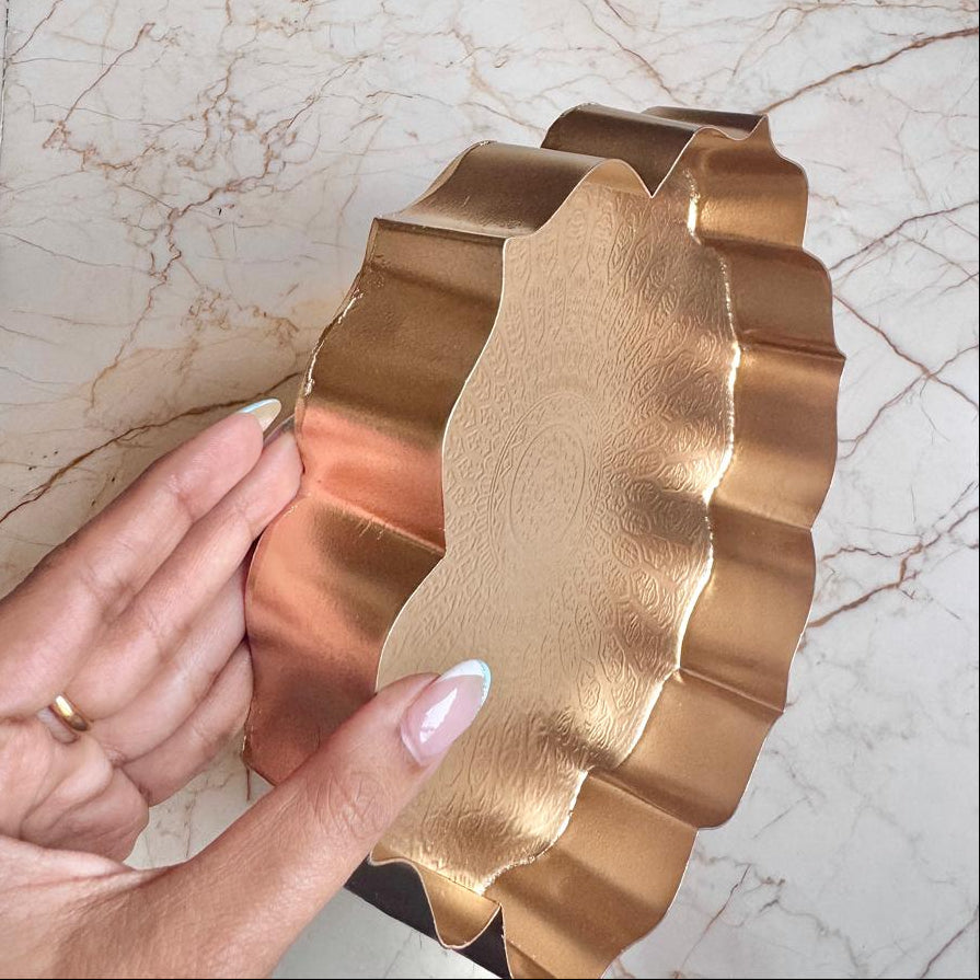 Hand holding a gold leaf-shaped object on a marble surface