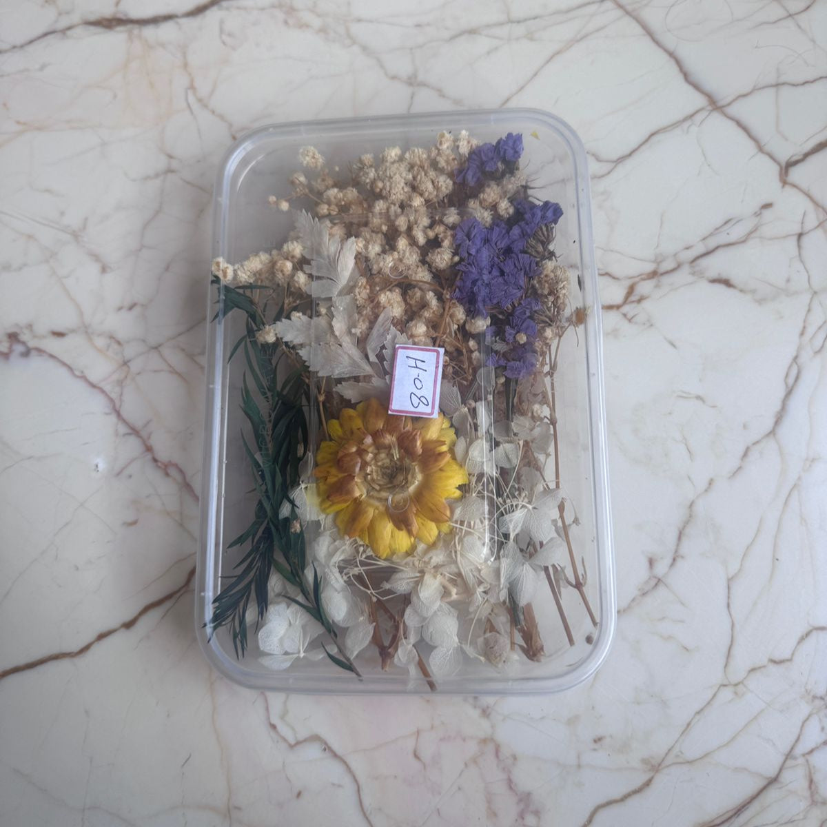 Clear container with dried flowers on a marble surface