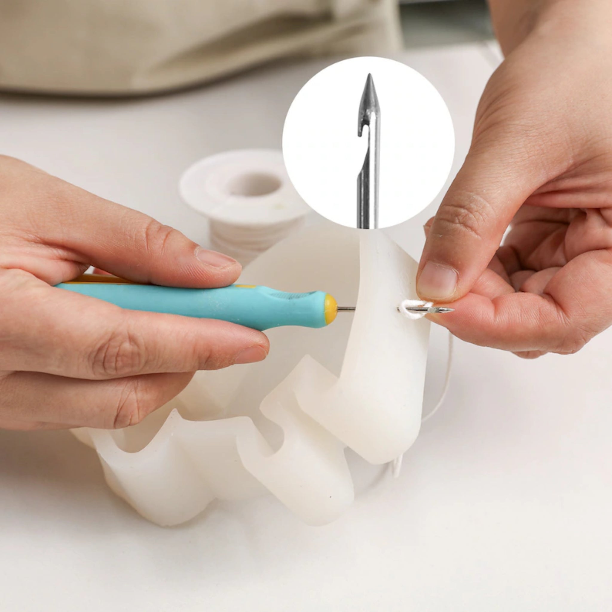 Person using a tool to remove a needle from a white container on a light background