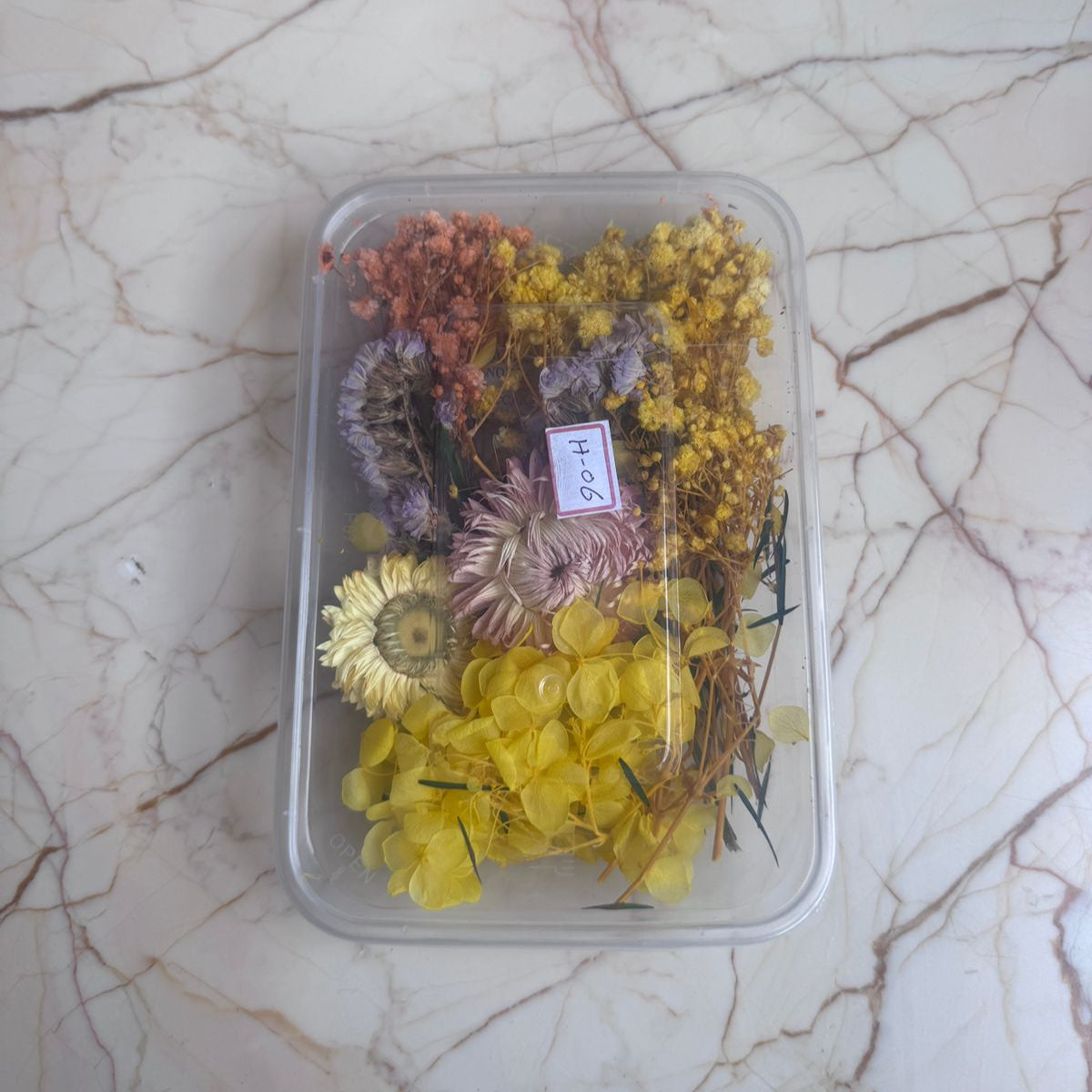 Clear container with dried flowers on a marble surface